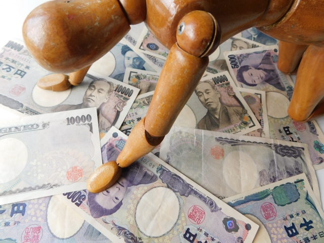 お金の上でうなだれる。喜多方市で借金返済の無料相談をする